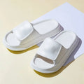 Pair of thick-soled white EVA flip-flop slippers with a non-slip patterned sole.