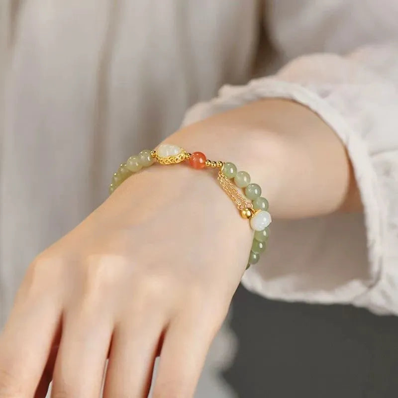 Qingshui jade women's bracelet with gold plated beads and a fu character charm.