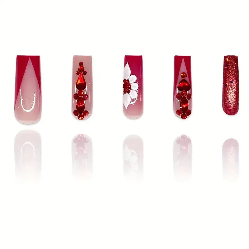 Long almond-shaped false nails with red diamond and floral art in sweet style.