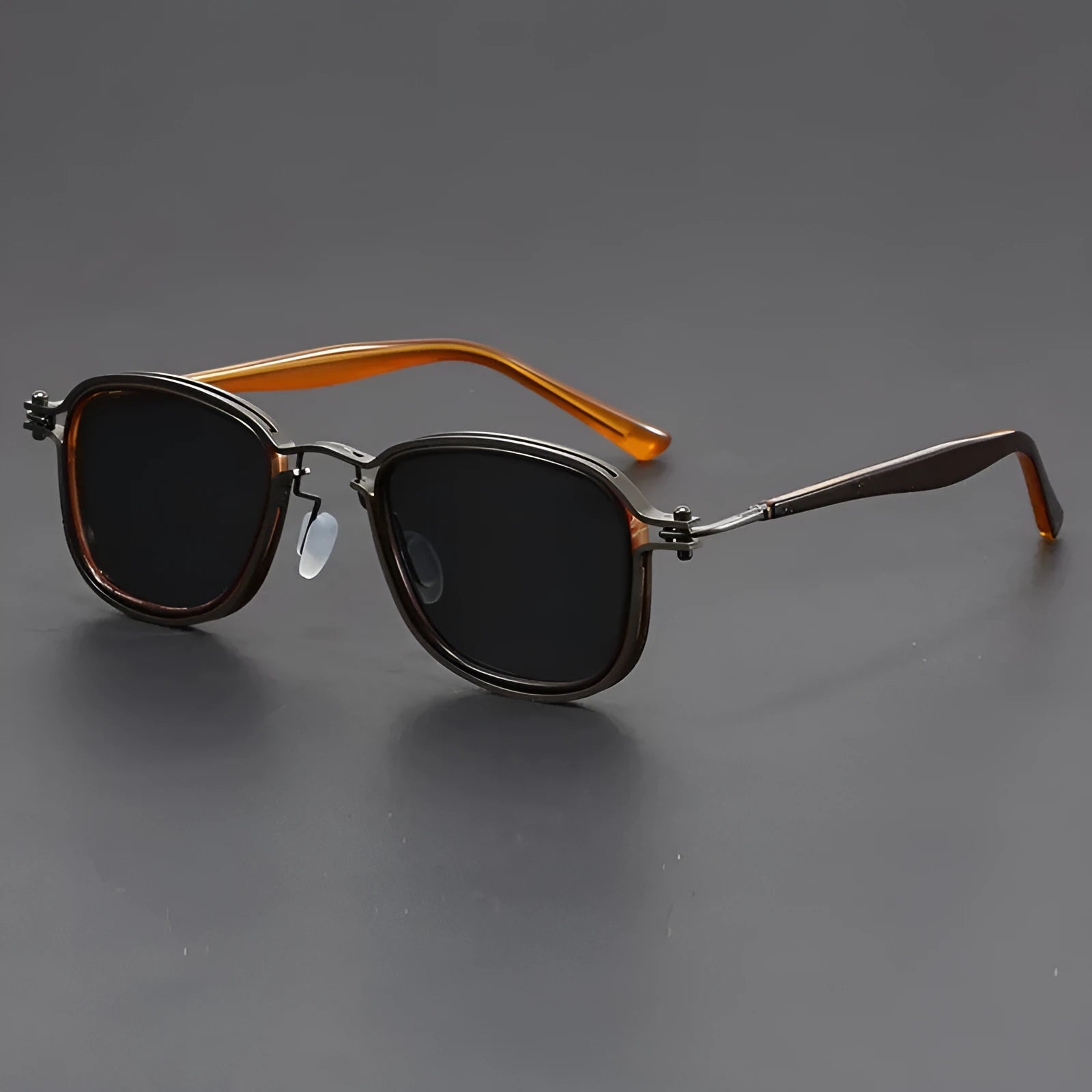 Retro square sunglasses with black gold frames and grey AC lenses on a wooden surface.