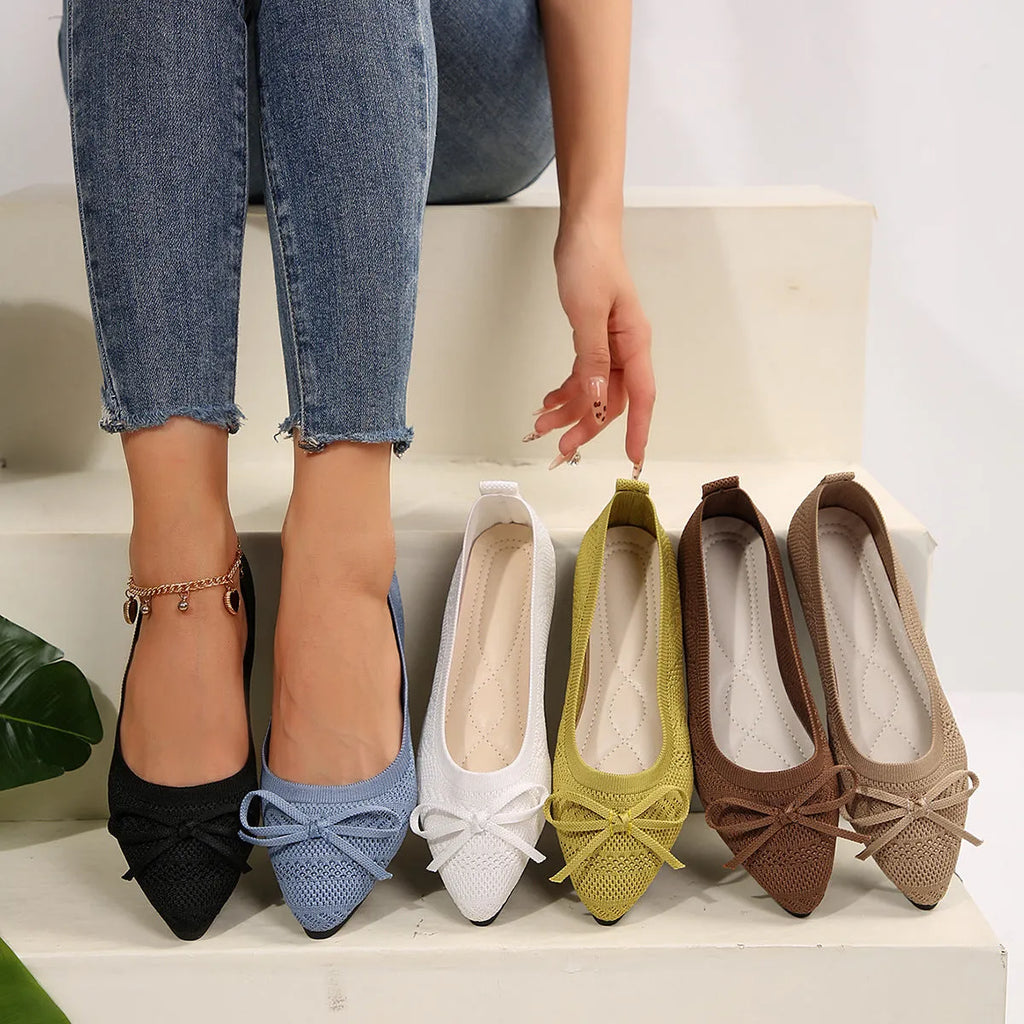Women's knitted flat shoes with a bow detail and pointed toe in various colours on a plain background.