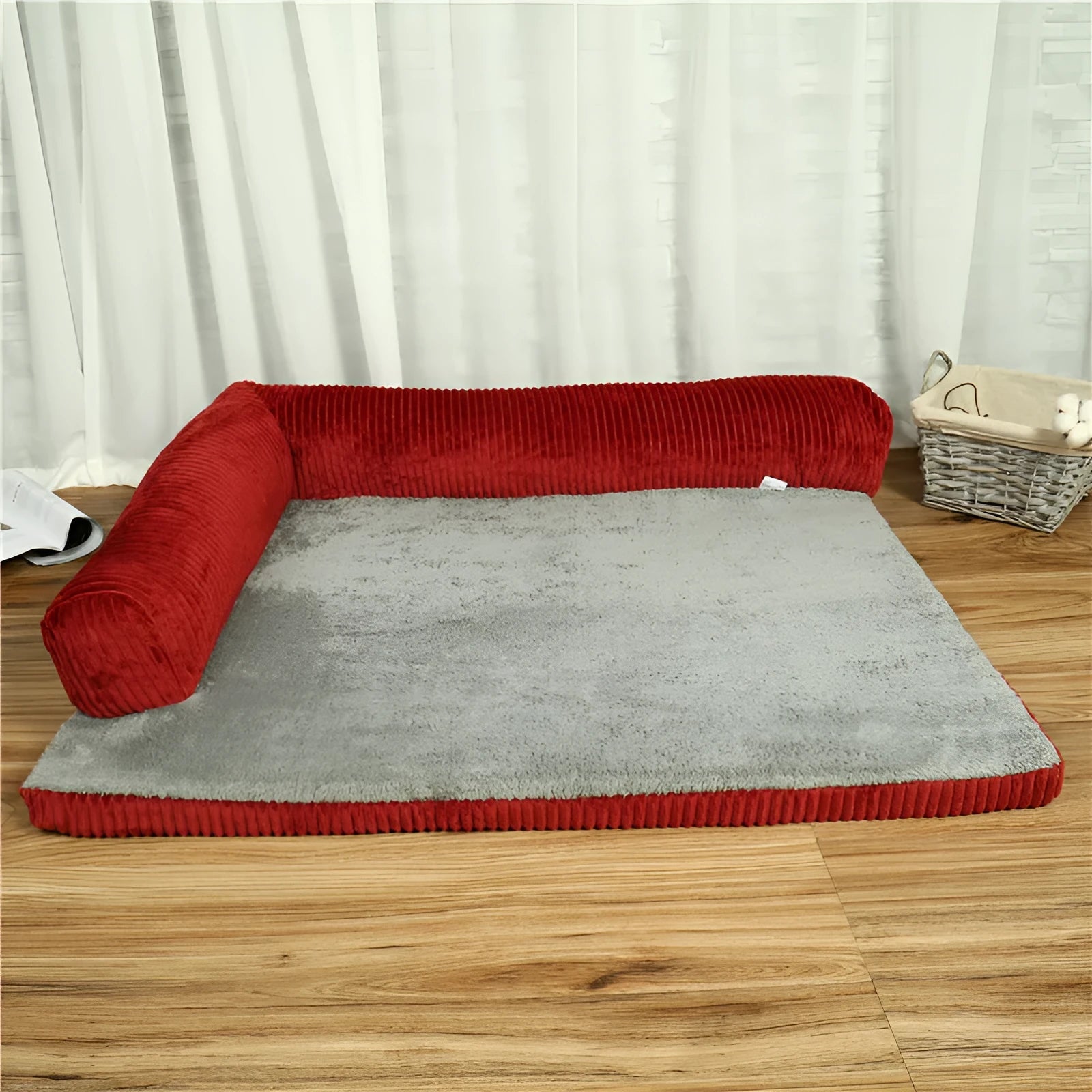 A corduroy dog sofa bed with a raised bolster side, shown in a grey colour on a wooden floor.