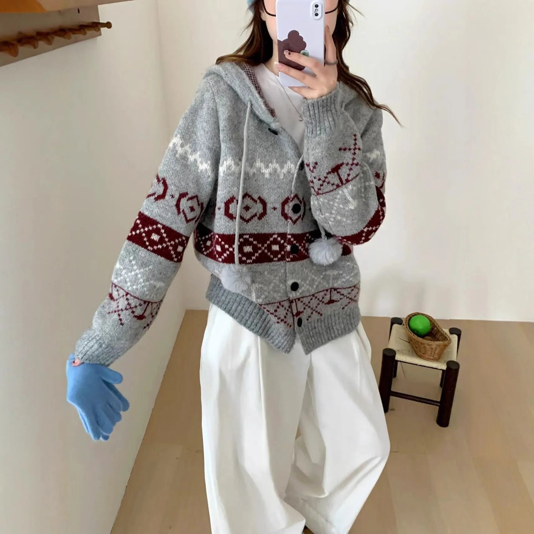 Woman wearing a beige loose-fit brocade sweater coat with a geometric pattern and long sleeves.