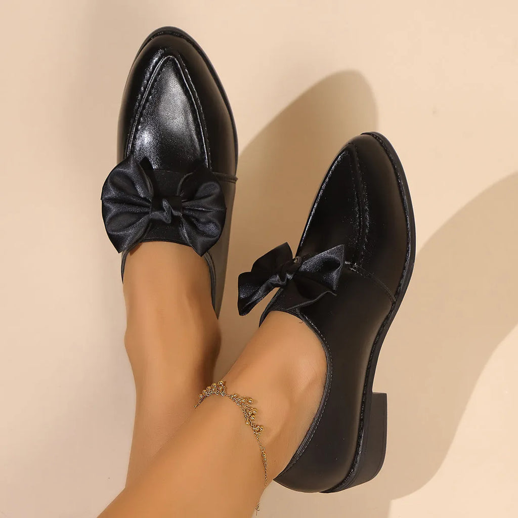 Women's simple leather-look shoes with a decorative bow, on a rubber sole.