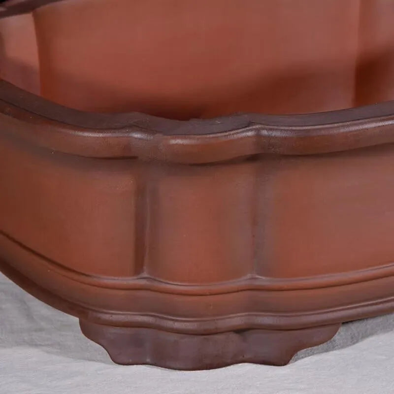 Large antique-style Chinese purple clay flowerpot with tree stump and floral relief pattern.