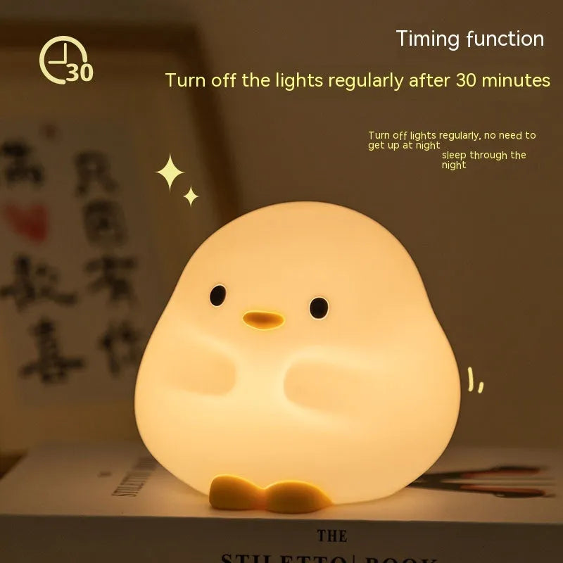 Cute duck-shaped silicone LED night lamp with touch sensor and warm glow on a bedside table
