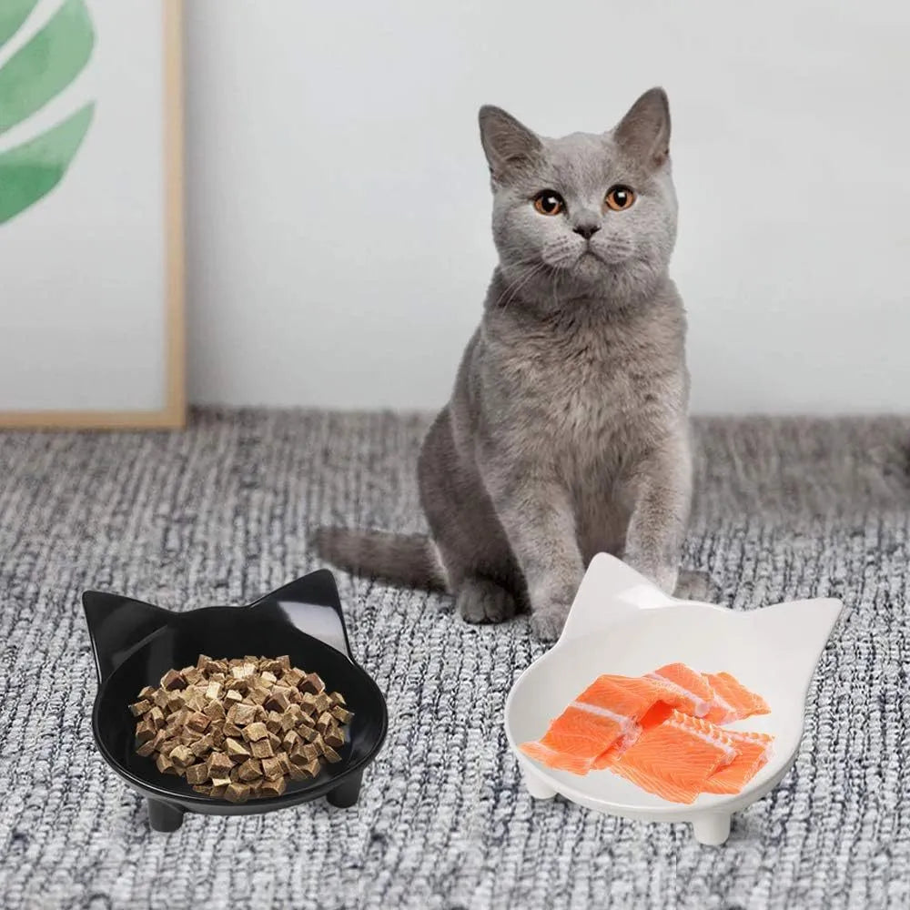 Shallow black and white melamine pet bowls with non-slip rubber bases on a kitchen floor.