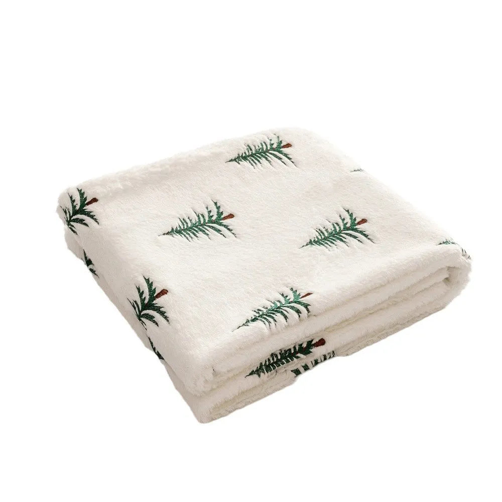 White plush sofa blanket with embroidered Christmas tree design on a sofa
