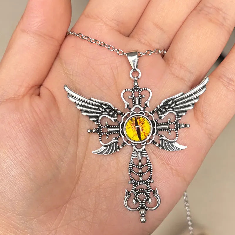 Close-up of a silver-coloured geometric pendant with wing details and a central cross on a chain.