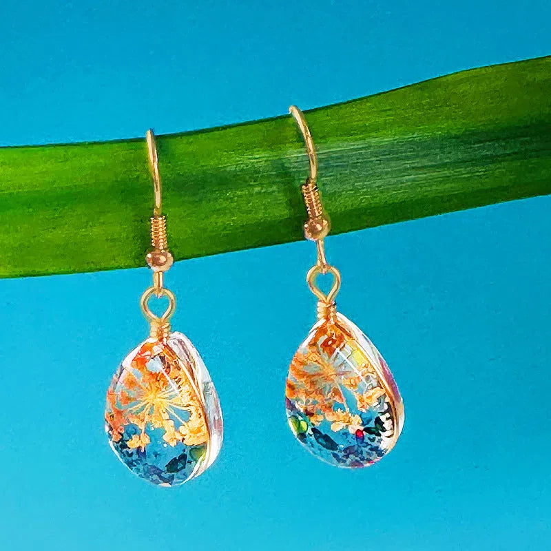 Water drop-shaped glass eardrops earrings with owl motif in ginger yellow and pink coloured glaze on a light background