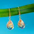 Water drop-shaped glass eardrops earrings with owl motif in ginger yellow and pink coloured glaze on a light background