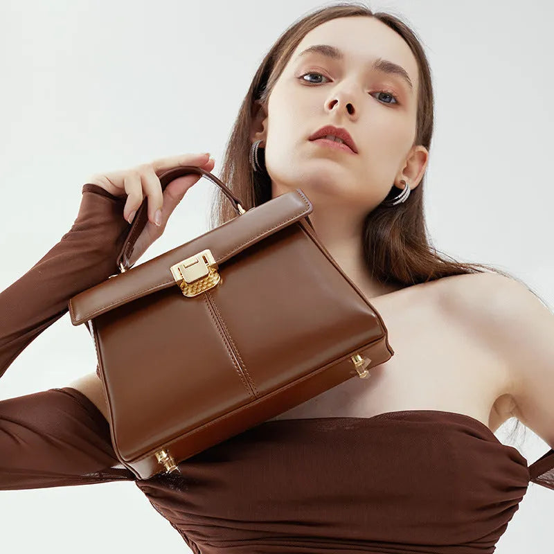 Women's black genuine leather shoulder bag with a clasp, shown with adjustable strap and open to reveal internal zippered pocket.