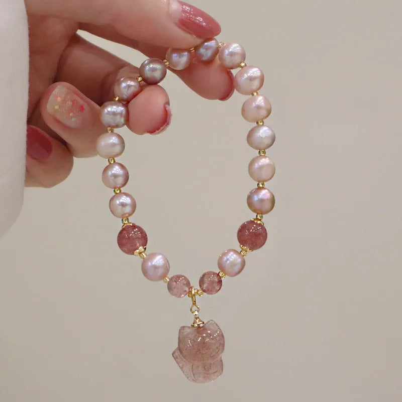 Women's light pink freshwater pearl and strawberry quartz bracelet with a silver fox charm on an adjustable chain.