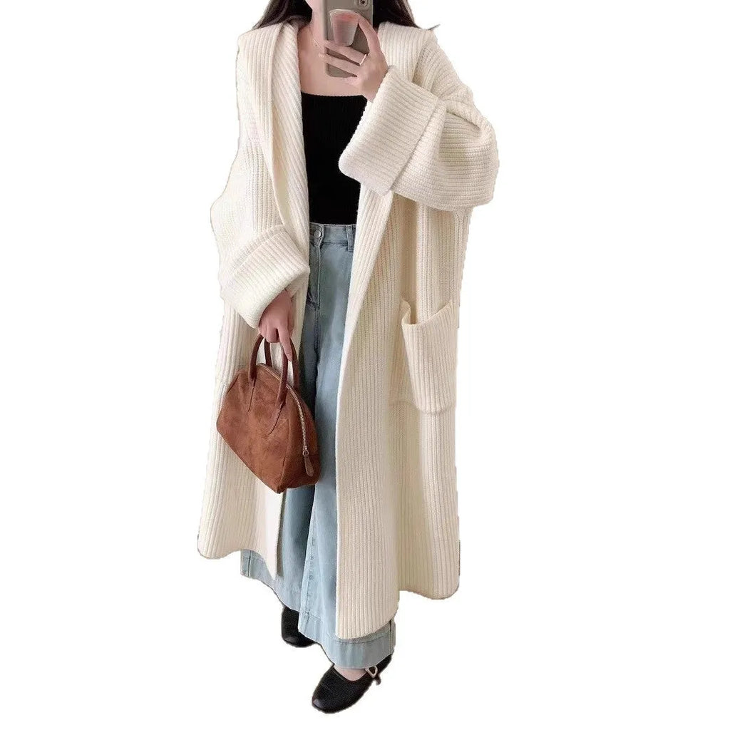 Woman wearing a longline loose grey hooded cardigan coat with raglan sleeves.