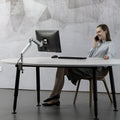 Aluminium alloy laptop stand with an adjustable air pressure arm in black colour on a wooden desk.