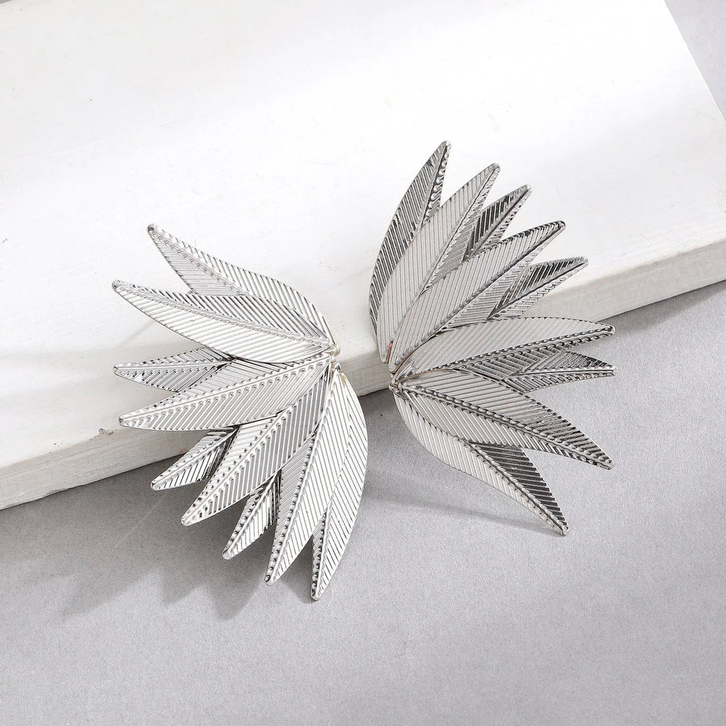 Gold and white alloy leaf-shaped patch earrings on a plain background
