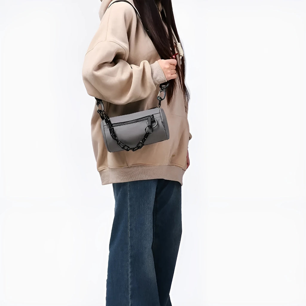 Black Oxford cloth messenger bag with a chain detail, worn crossbody.