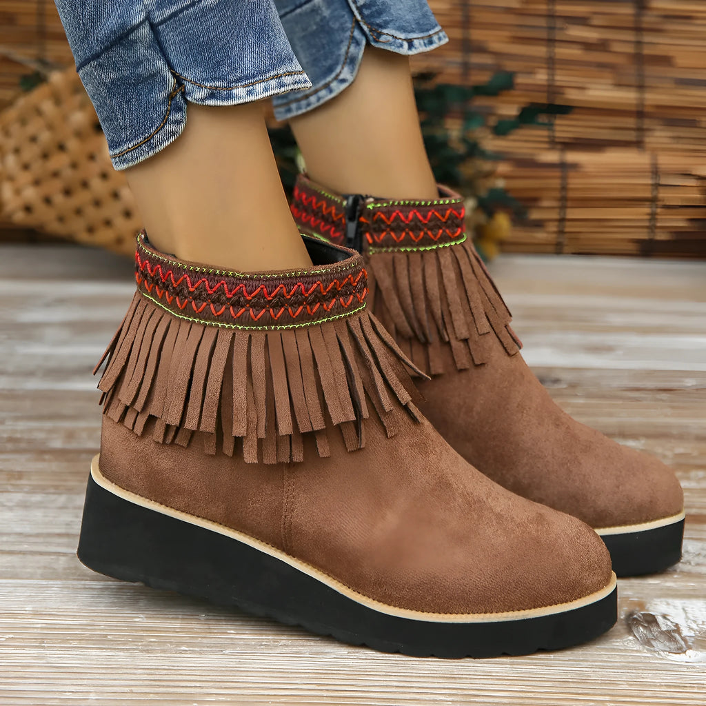 Women's suede ankle boots with a thick wedge platform sole, side zipper, and tassel detail in dark brown.