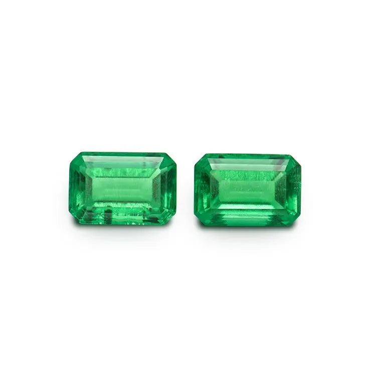 A loose cultivated emerald gemstone in a columbia green treasure colour on a white background.