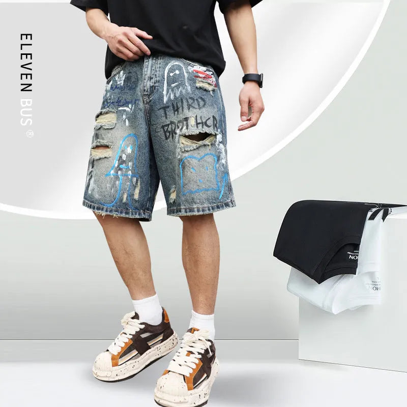 Blue men's ripped denim shorts with graffiti style and straight leg cut on a hanger.