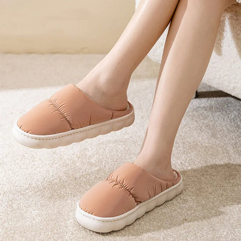 A pair of thick-soled house slippers with an artificial leather upper and plush lining, shown in a selection of colours.