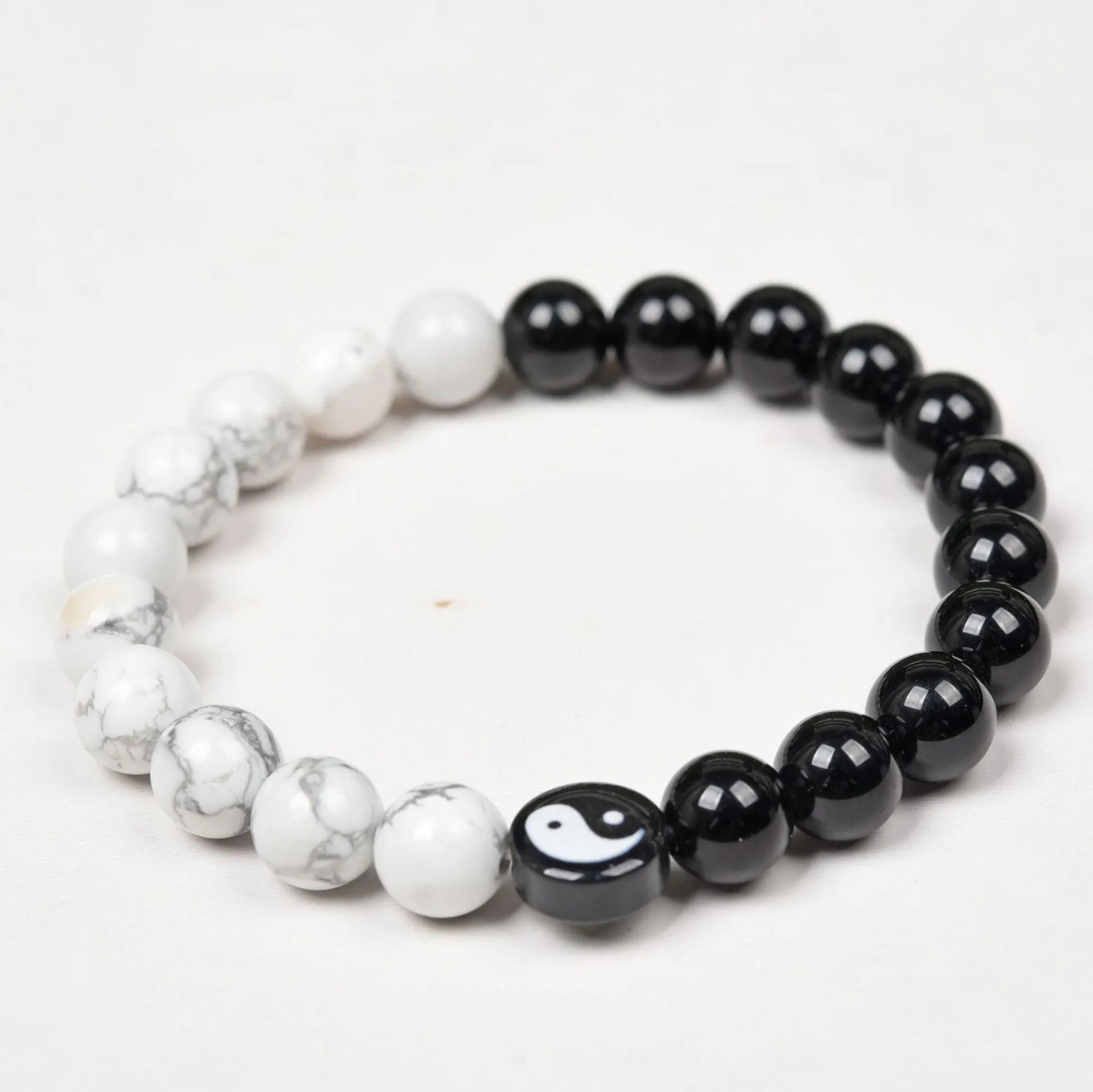 Natural obsidian and white turquoise 8mm bead bracelet on a neutral background