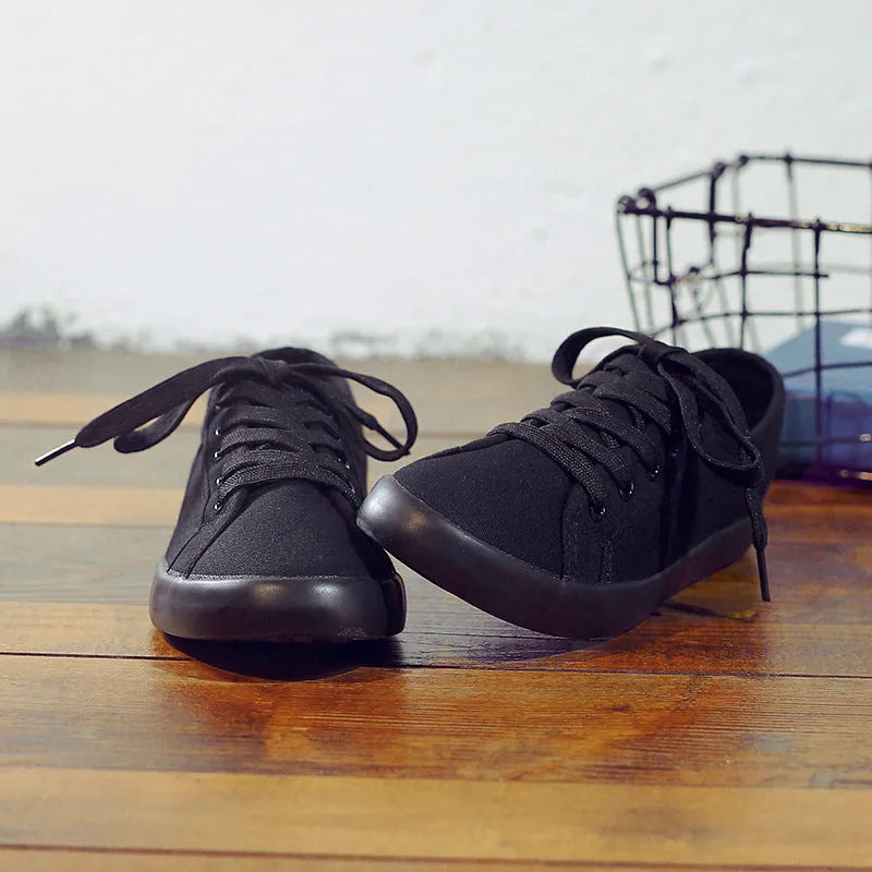 All black women's canvas lace-up work shoes with flat rubber sole on a white background.