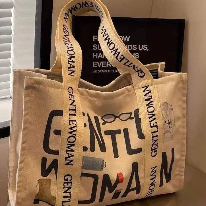 Large canvas women's tote bag with printed design, shown in shopping and travel use contexts.