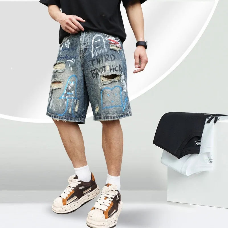 Blue men's ripped denim shorts with graffiti style and straight leg cut on a hanger.