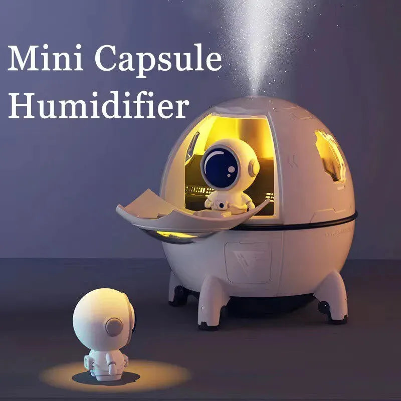 Astronaut-themed portable USB humidifier with blue LED light on a desk next to a laptop.