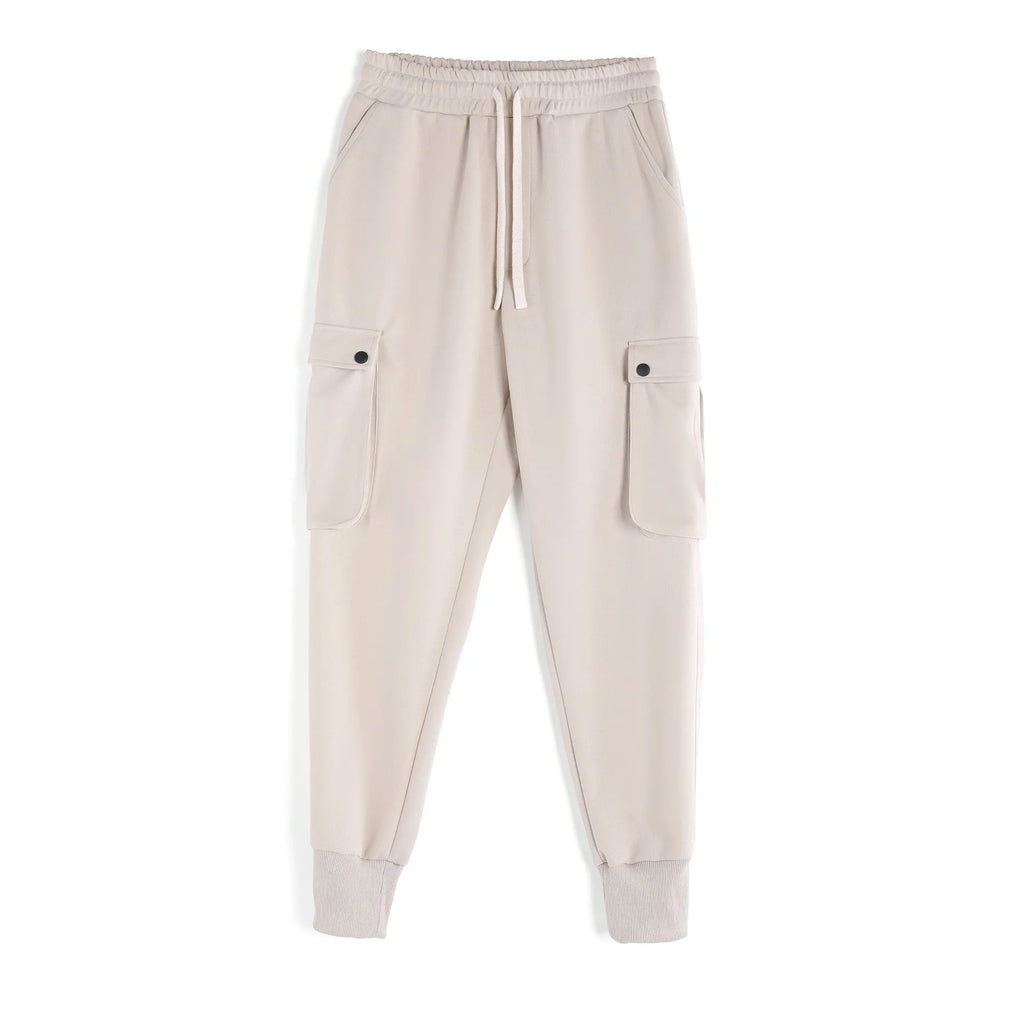 Men's loose-fit beige cotton trousers with tied ankle cuffs and multiple pockets on a neutral background.
