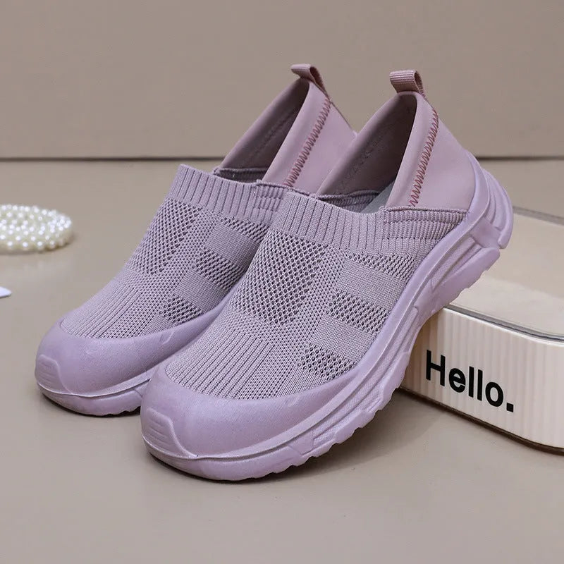 Women's black slip-on shoe cover with breathable cloth upper and flat PVC sole.