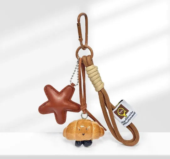 Solid brass handbag pendant featuring a handmade soda bread cartoon charm on a brown carrying strap.