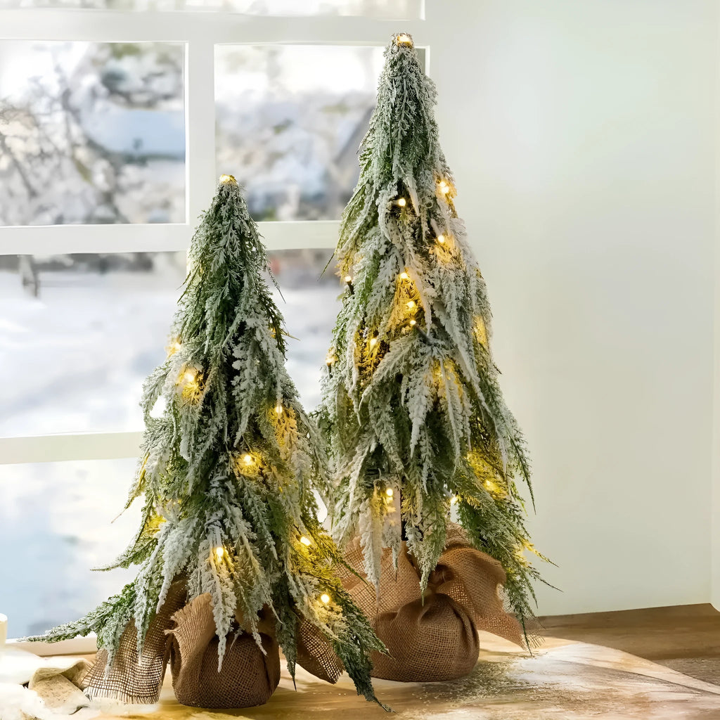 Small 24-inch white artificial Christmas tree with LED lights and snow effect on a desktop