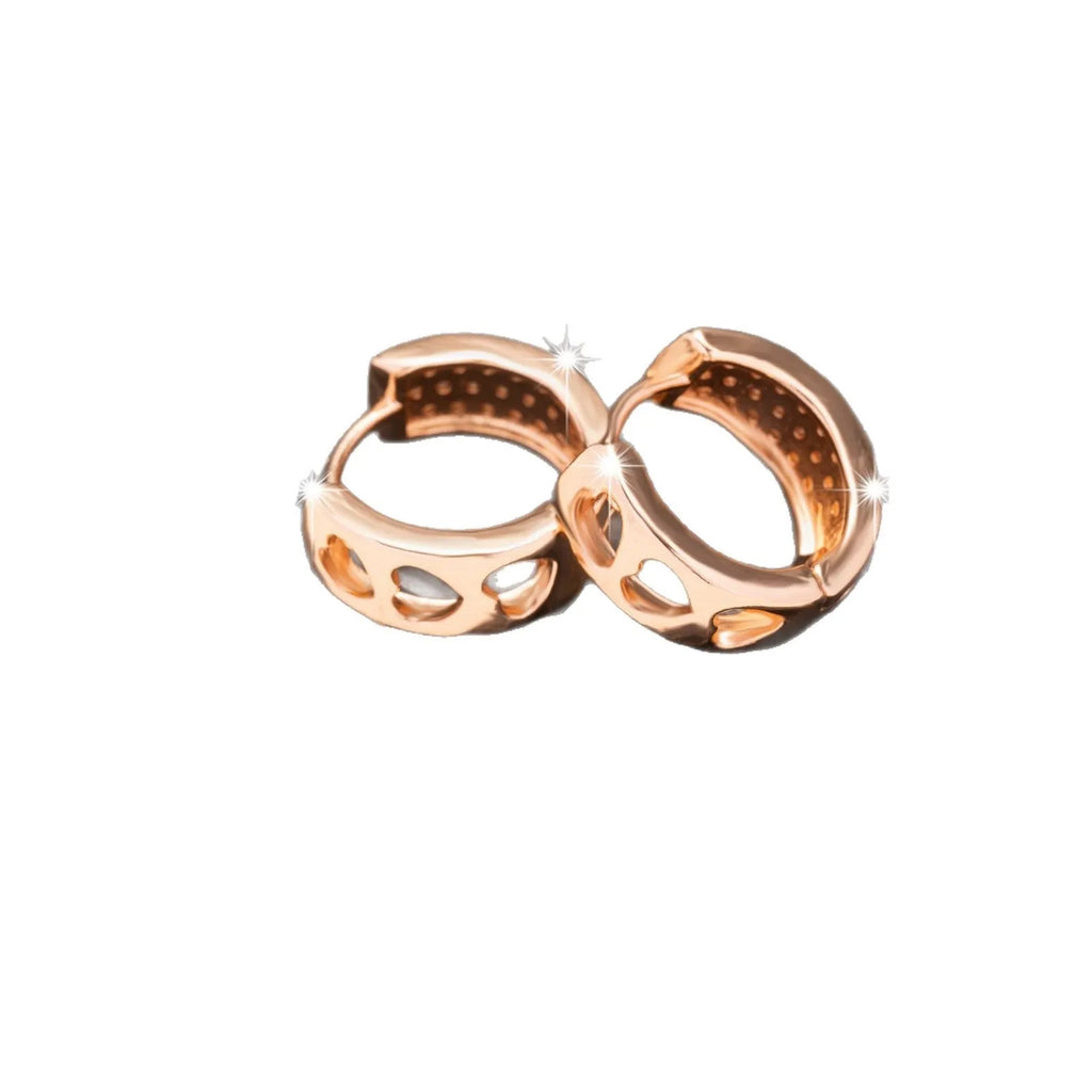 A pair of circular rose gold tone earrings featuring a hollowed-out heart shape design on a white background.