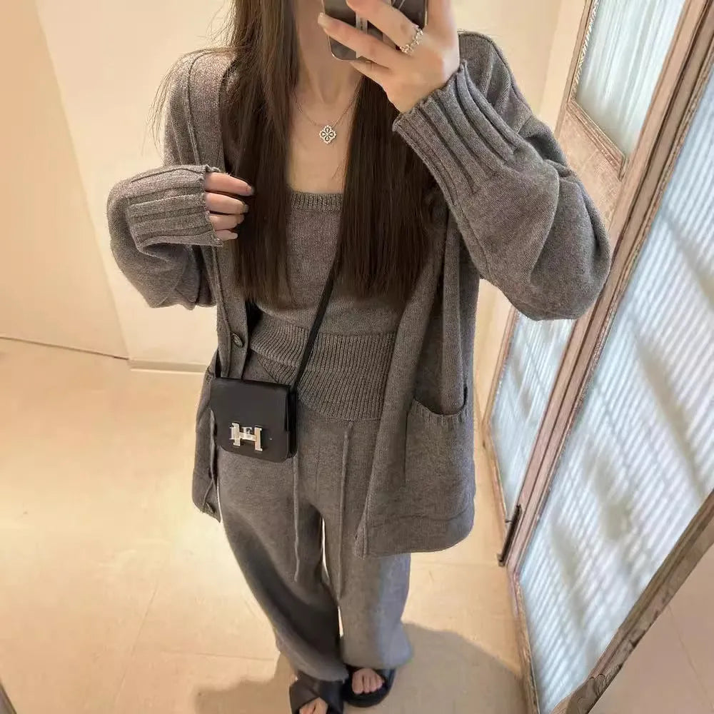 Women's light brown wool blend knit cardigan, vest, and trousers three-piece set laid flat.