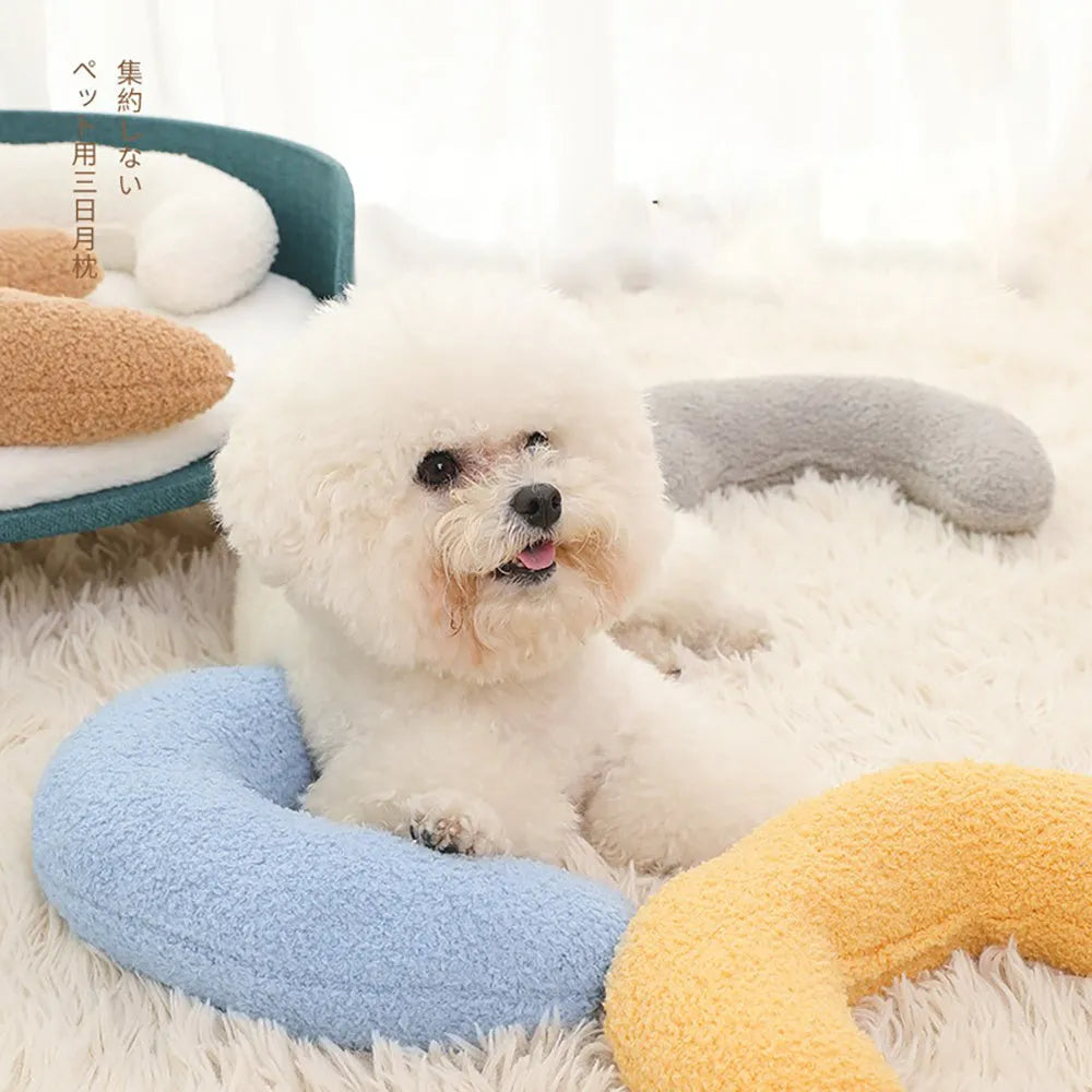 Blue U-shaped cat pillow with a white adjustable padded collar on a grey sofa.