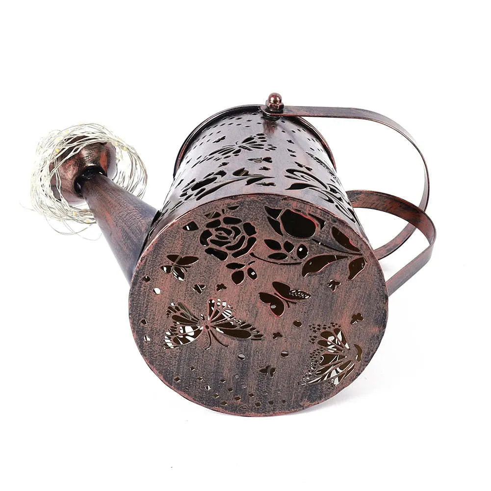 Solar-powered iron garden lamp with a tapered butterfly pattern emitting warm white light.