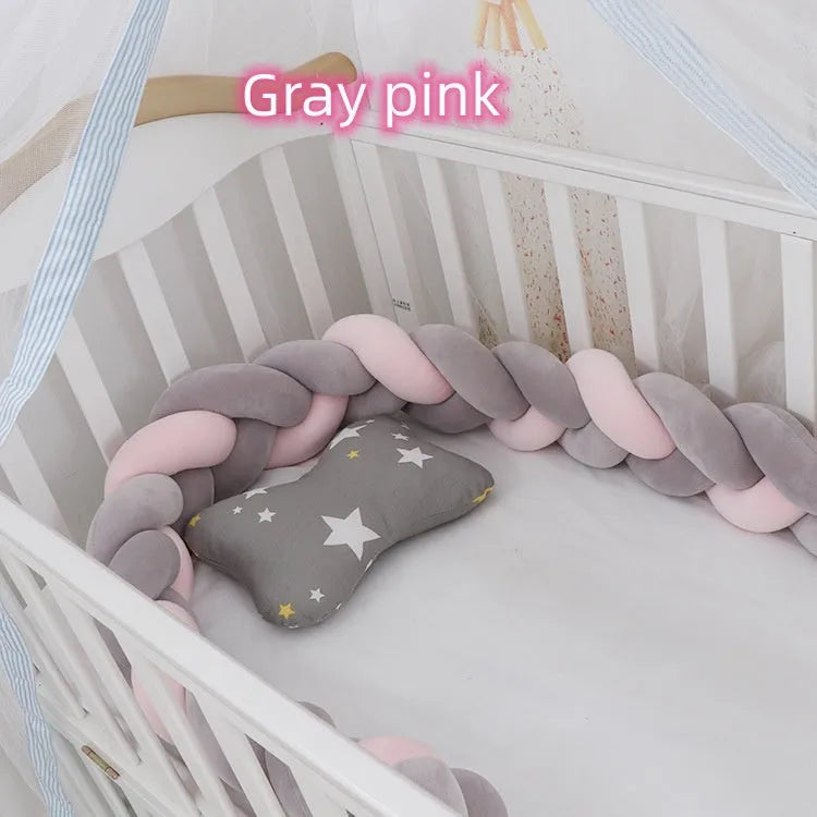 Braided knot style crib bumper in spandex velvet, wrapped around white cot rails in a nursery.