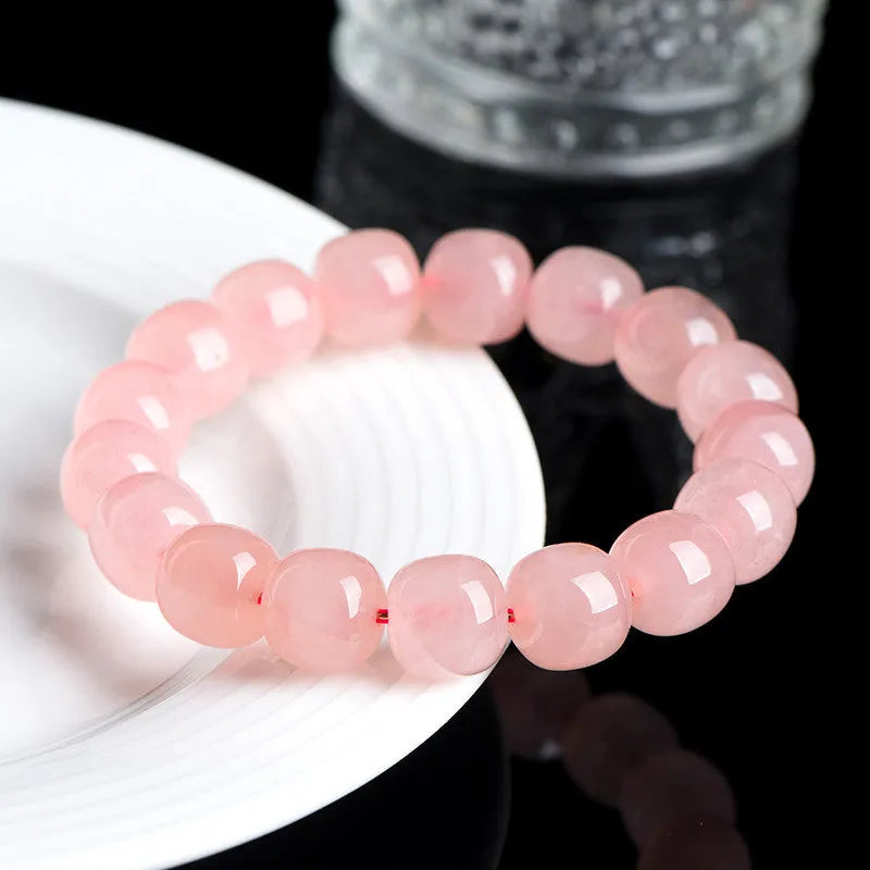 Pink natural crystal bracelet with barrel-shaped beads on a wrist.