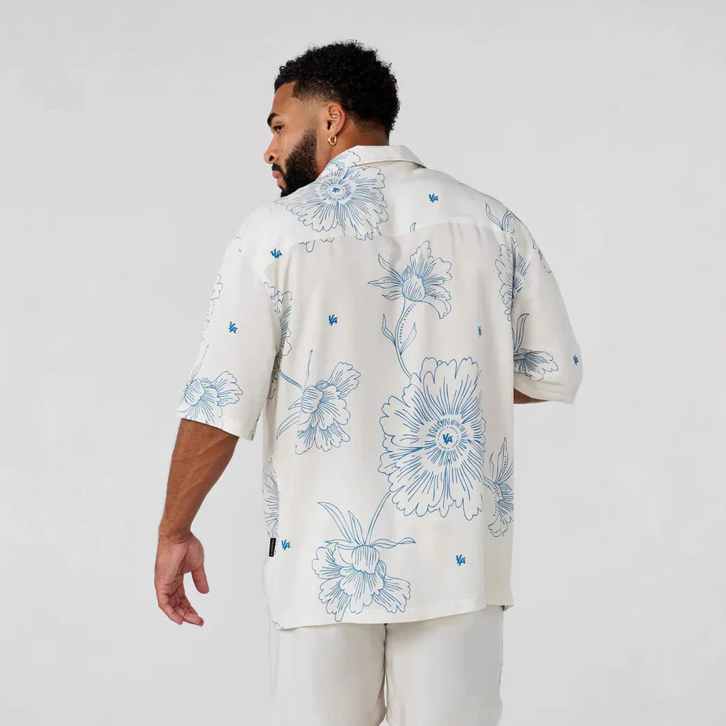 Man's loose-fitting printed short sleeve top in a light colour, showing cardigan style and floral pattern detail.