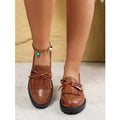 Women's black flat loafers with a decorative bow on the upper, made from artificial PU leather.