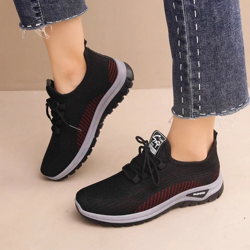 Women's black mesh sneakers with cross strap detail and round toe on a rubber sole.