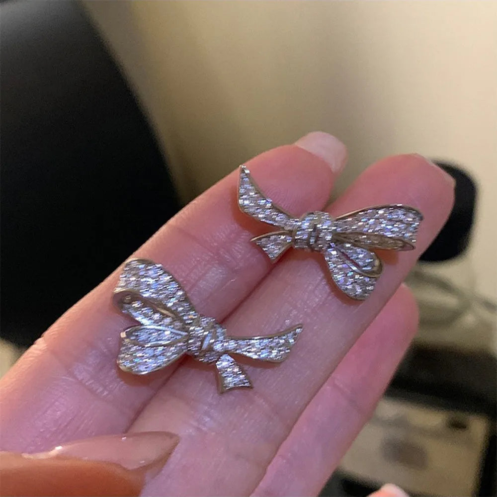 Gold electroplated bowknot ear studs with miniature zircon inlay and 925 silver needle on white background