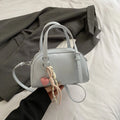 Soft PU women's shoulder bag in shell shape with sandwich pocket, shown in black with pendant strap.