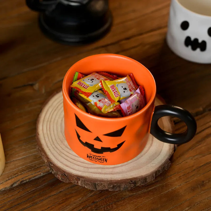Orange ceramic pumpkin-shaped mug with handle on a table beside a dessert spoon and gift box.