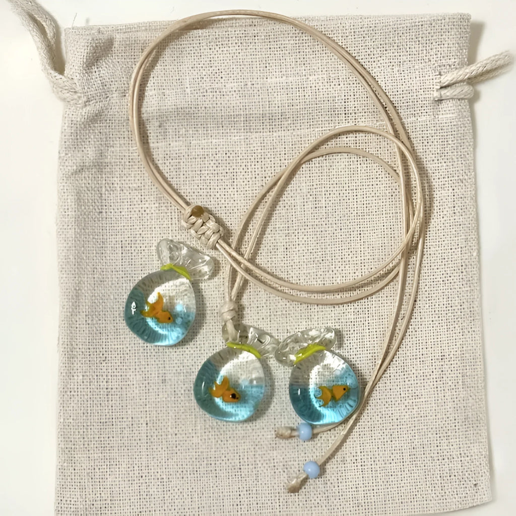 Women's necklace with a blue hand-painted fish charm on a beige cotton and linen clavicle chain.