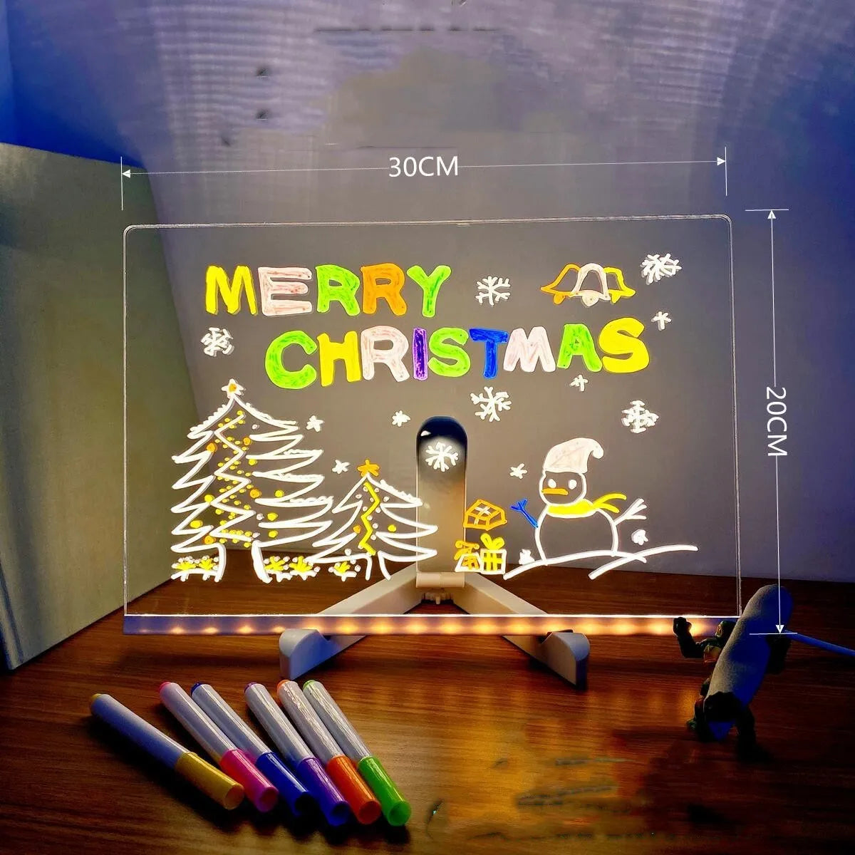 DIY acrylic LED message board on a desk with handwritten notes, glowing softly, next to colourful pens.