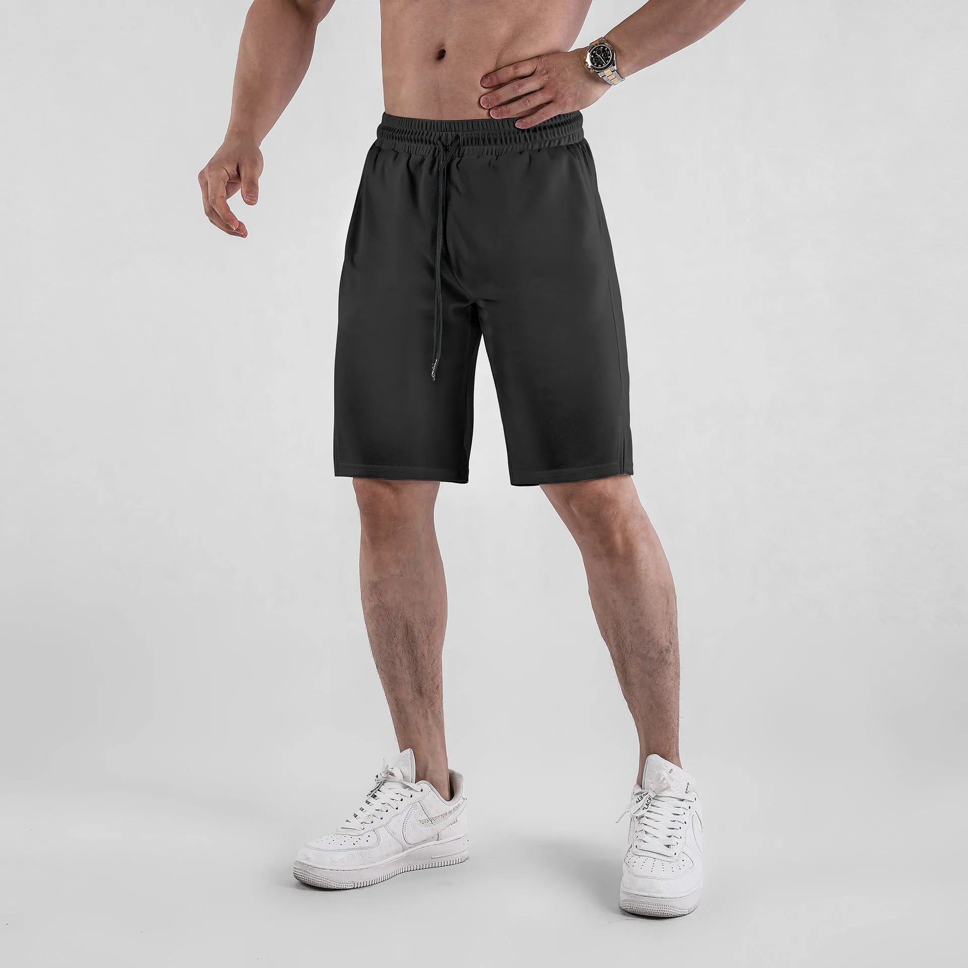 Man wearing black loose-fit mesh casual shorts with an elastic waistband.