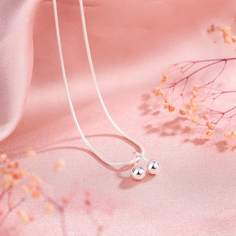 Close-up of a silver cherry pendant necklace on a textured snake bone chain, adjustable from 21cm to 50cm.